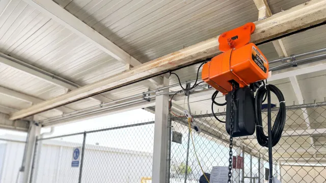 Polipasto eléctrico de cadena Hitachi instalado en una viga de nave industrial.